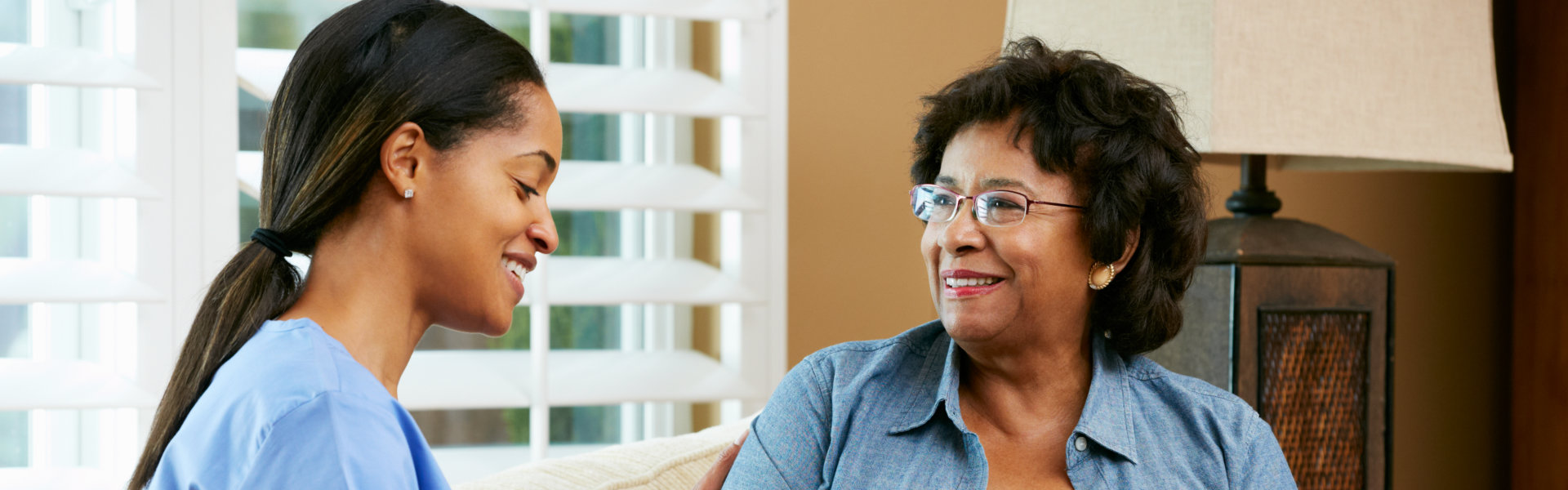 Nurse Visiting Senior Female Patient At Home Smiling
