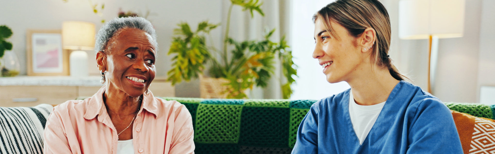 an elder and a caretaker talking on a sofa